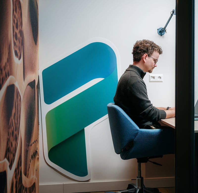 Rebel aan het werk in het belhokje met een groot Power Platform bord achter zich
